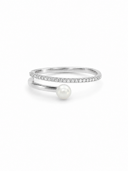 Freshwater pearl crossover ring in white gold with one slim clear pavé arc and one smooth pearl-tipped arc on a white background.
