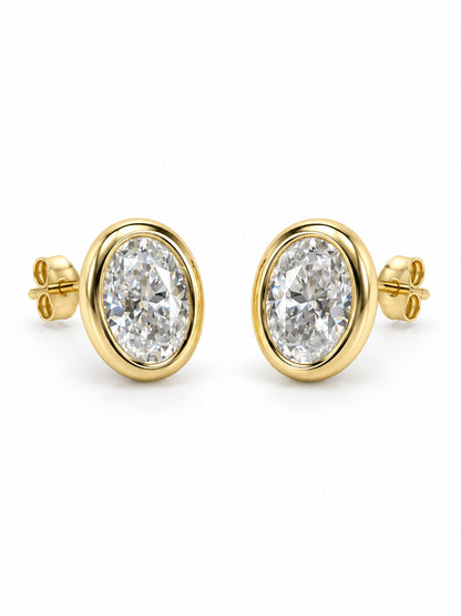 Three-quarter view of Golden Hour oval moissanite bezel studs with posts and butterfly backs