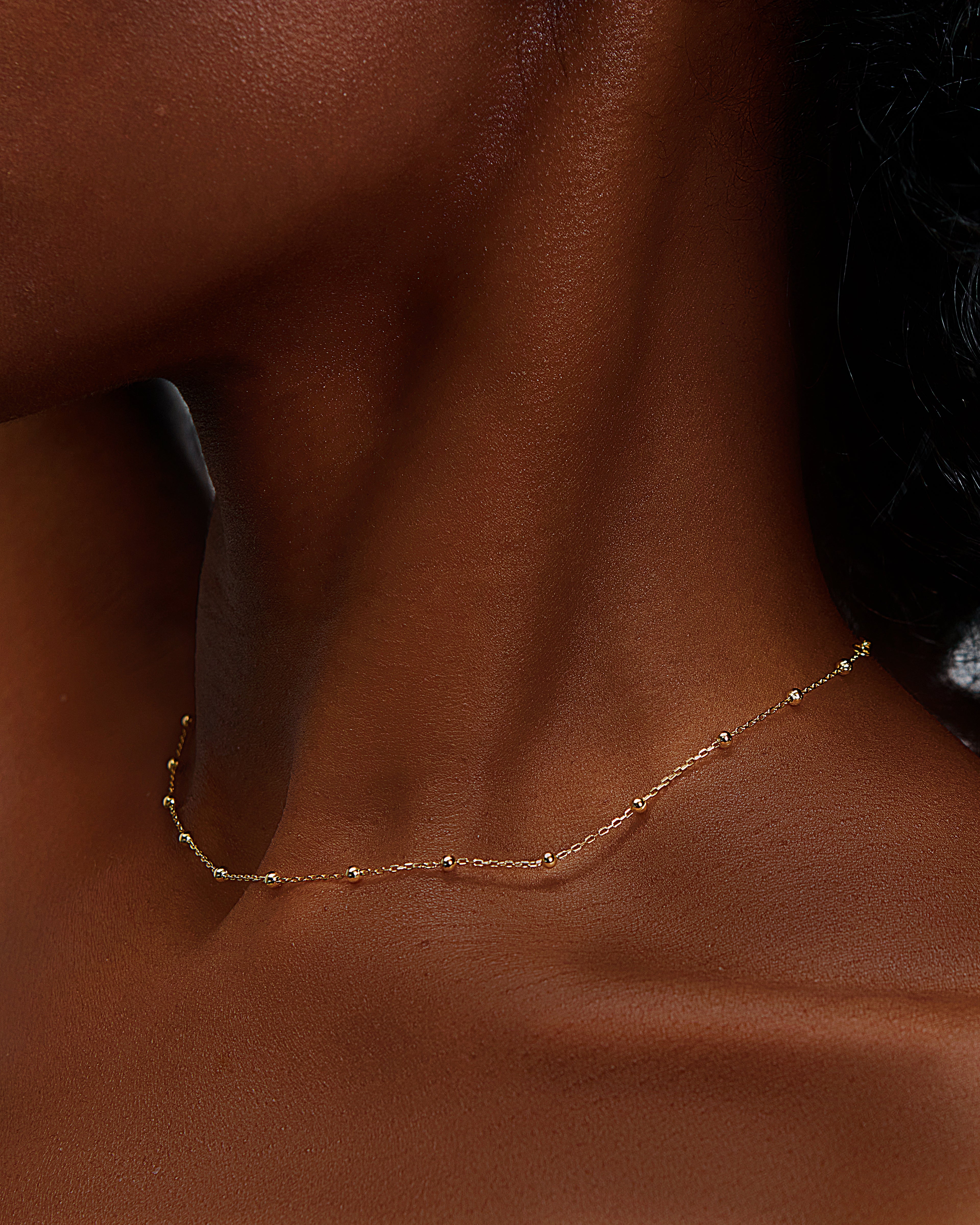 Featturing a beautiful elegant simple necklace on a black female with glowing skin. the Image shows that our jewelry feels like second skin, meaning that its comfortable and weightless.