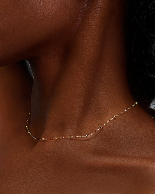 Featturing a beautiful elegant simple necklace on a black female with glowing skin. the Image shows that our jewelry feels like second skin, meaning that its comfortable and weightless.