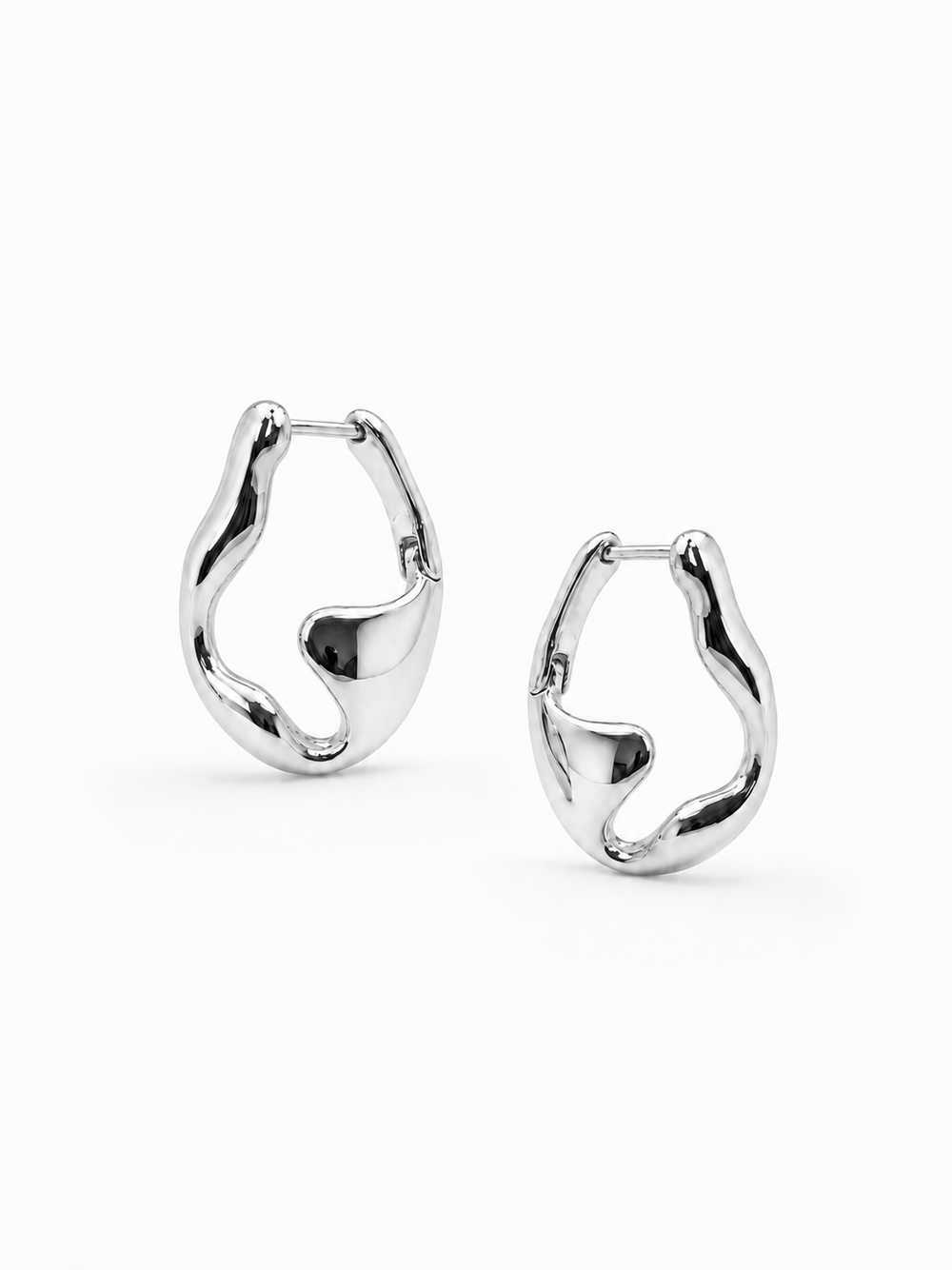 Mirrored pair of sculptural white-gold wave hoop earrings, with the left earring higher and the right earring slightly lower on a white background.