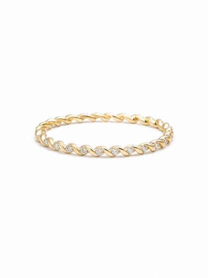 Slim twisted pavé band ring in yellow gold with repeating polished diagonal folds and tiny clear stone accents on a white background.