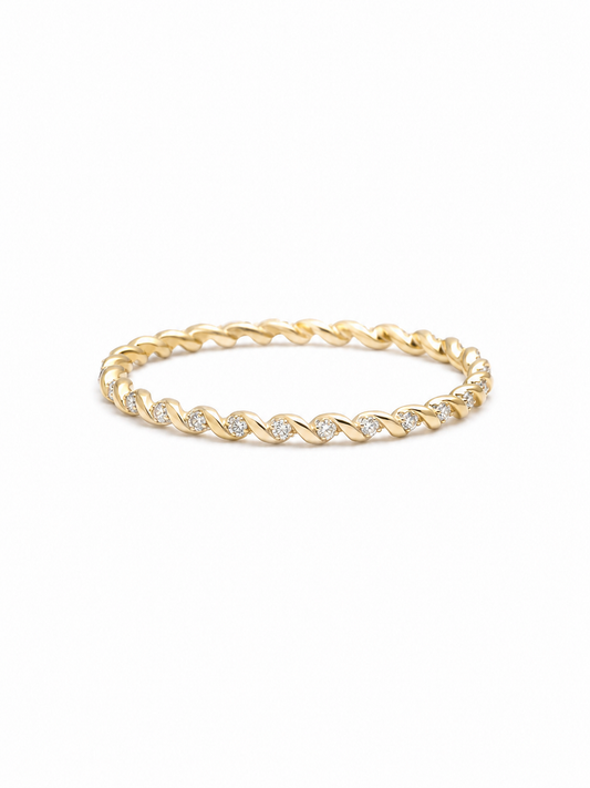 Slim twisted pavé band ring in yellow gold with repeating polished diagonal folds and tiny clear stone accents on a white background.